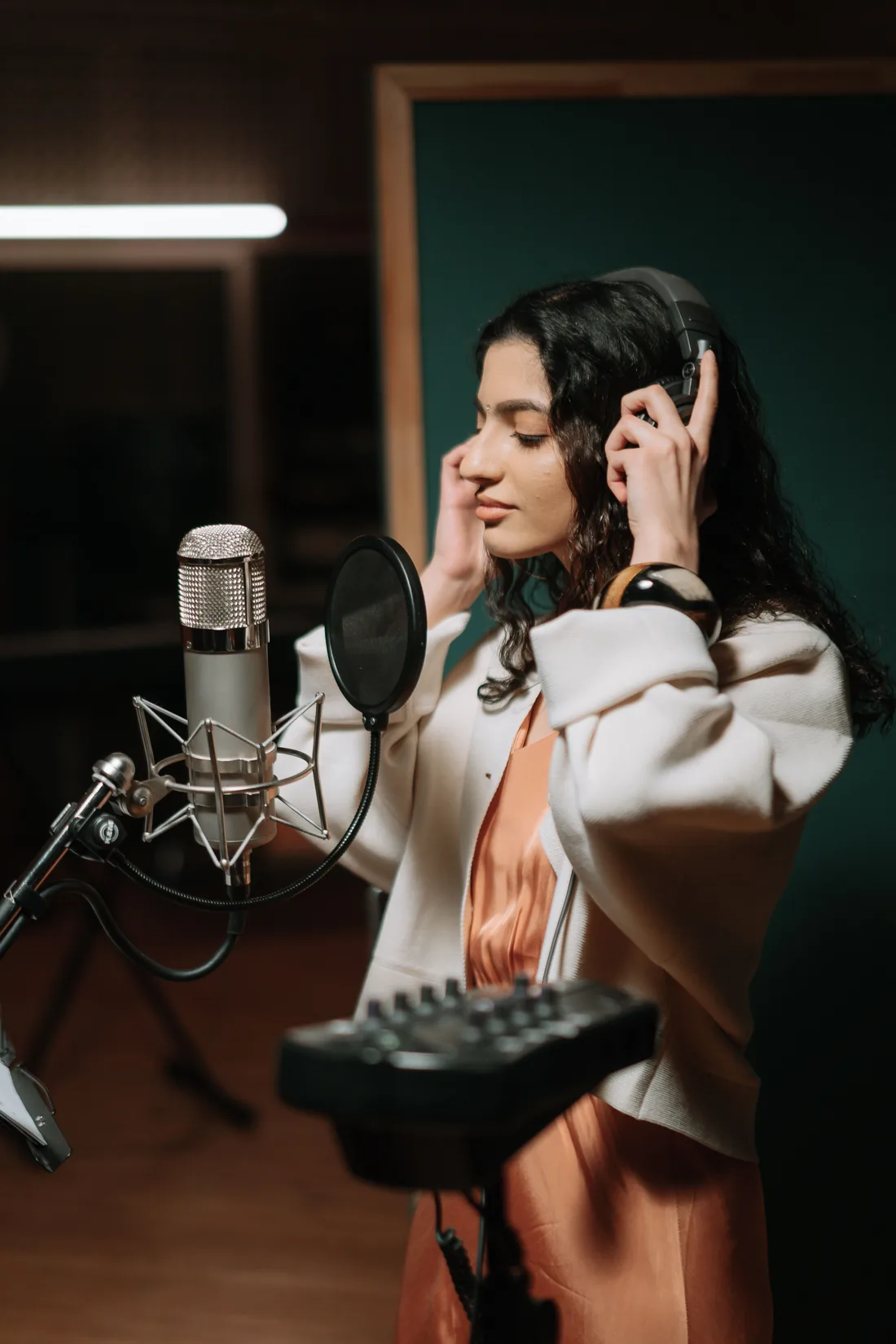 A vocalist recording in a studio booth